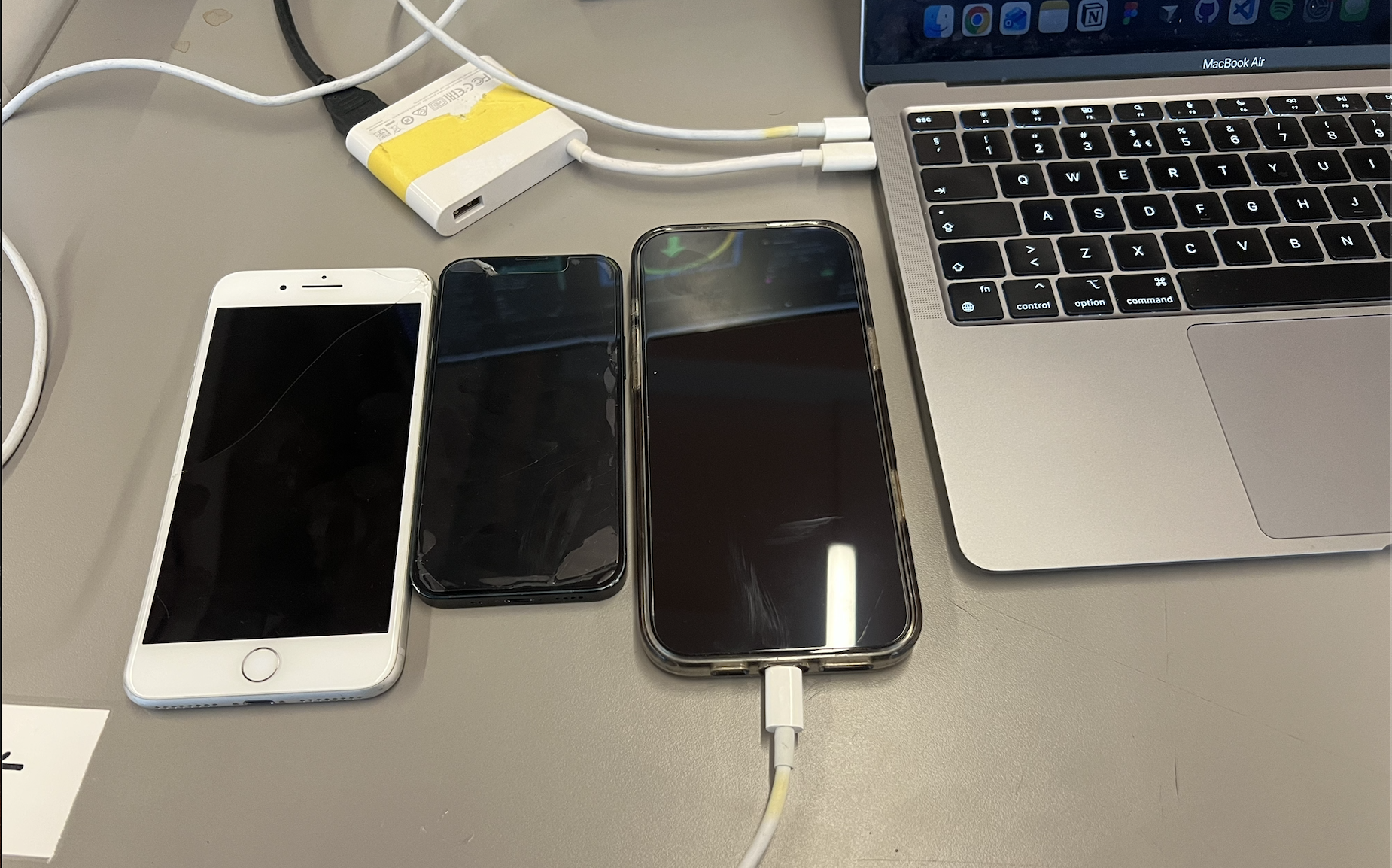 Three phones and a MacBook Air on a desk during testing